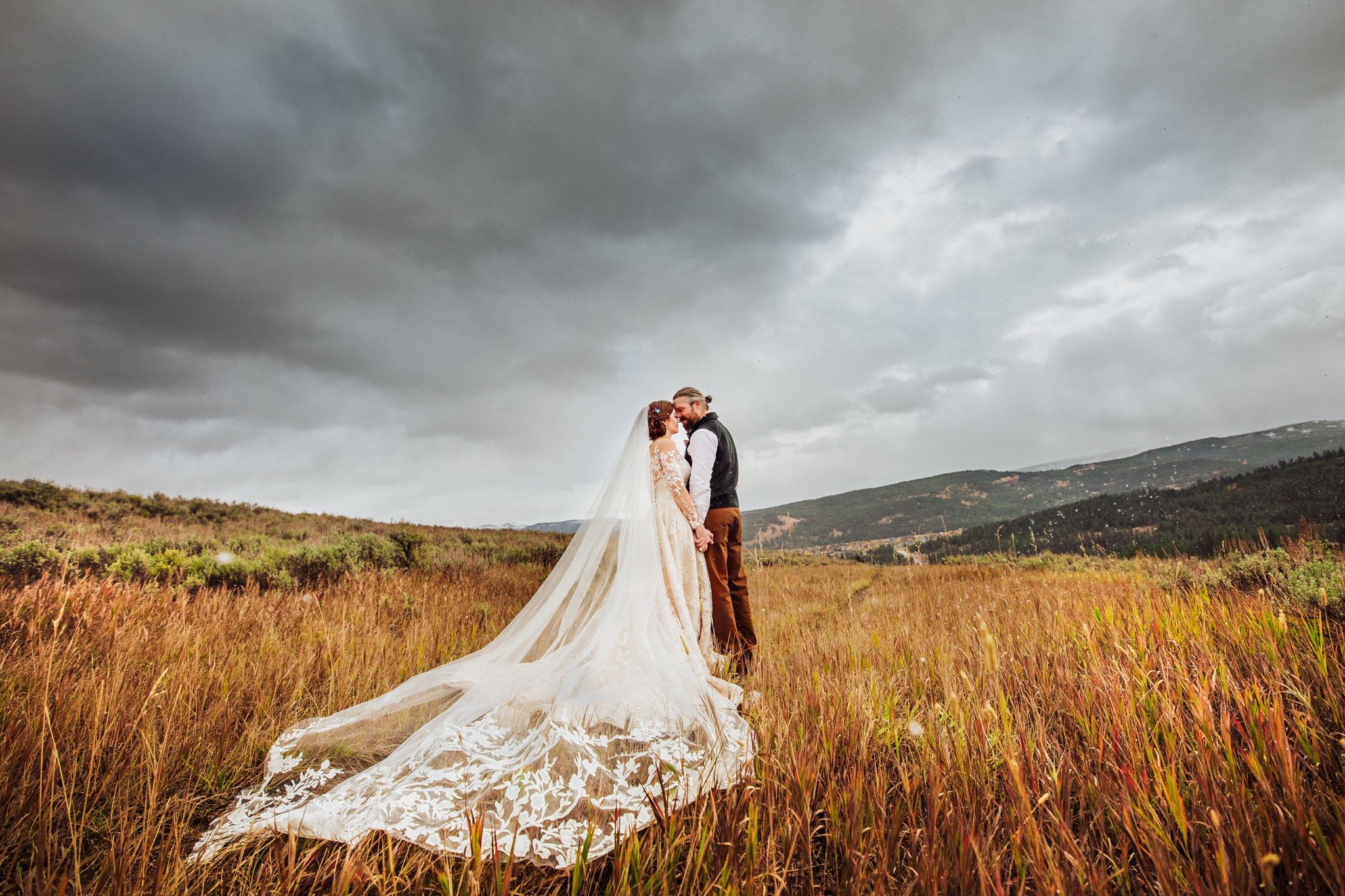 Bride and Groom standing in a field wearing a Gown Gallery dress