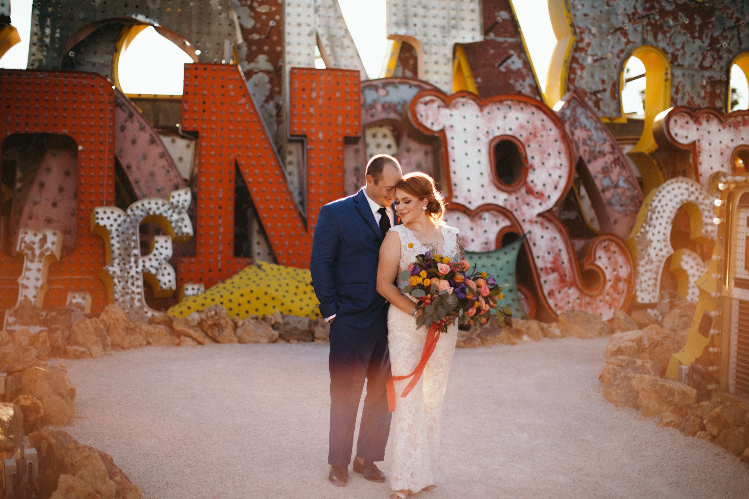 Bride and groom standing in front of large vintage signs.