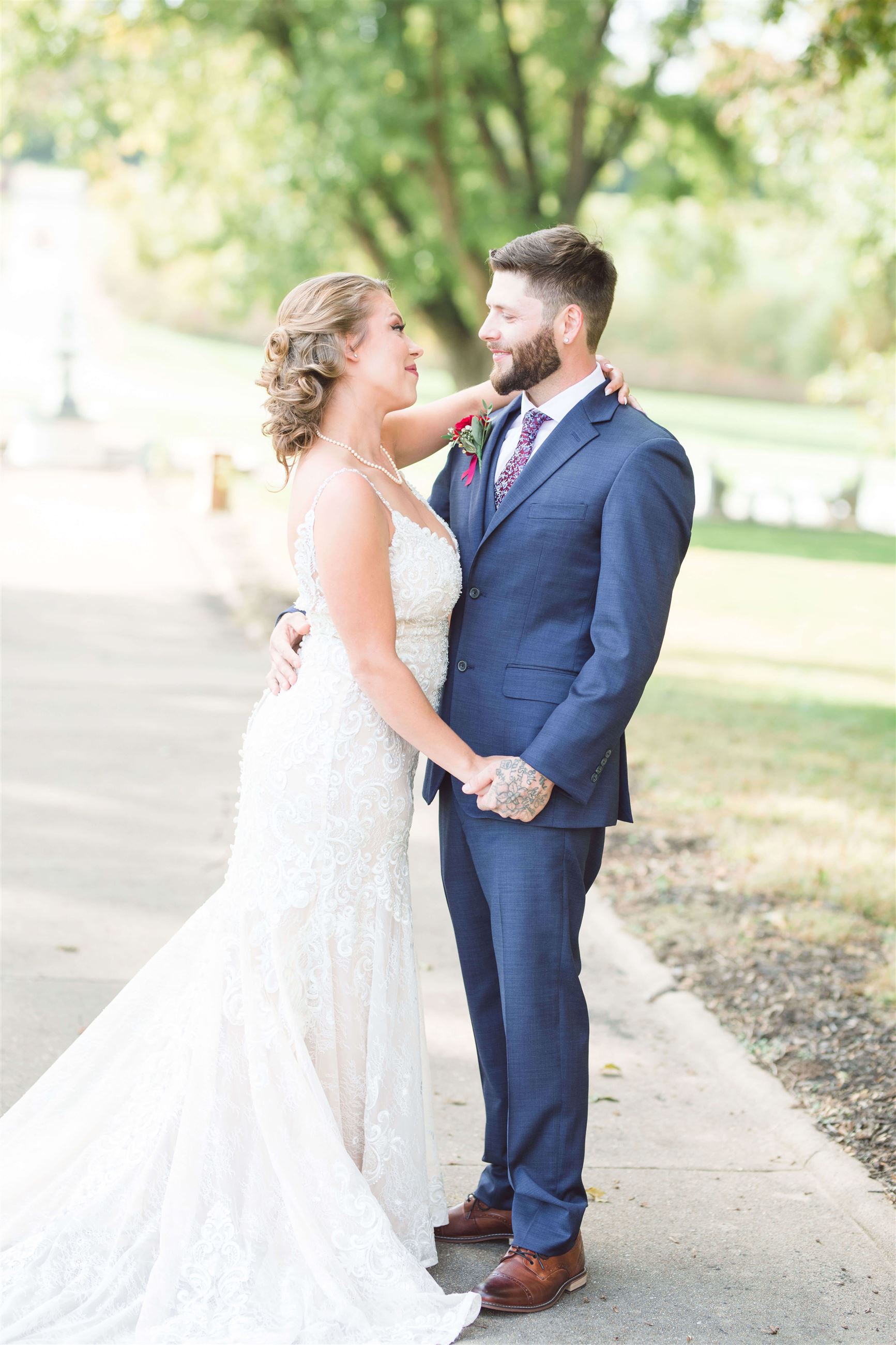 bride and groom standing in a park