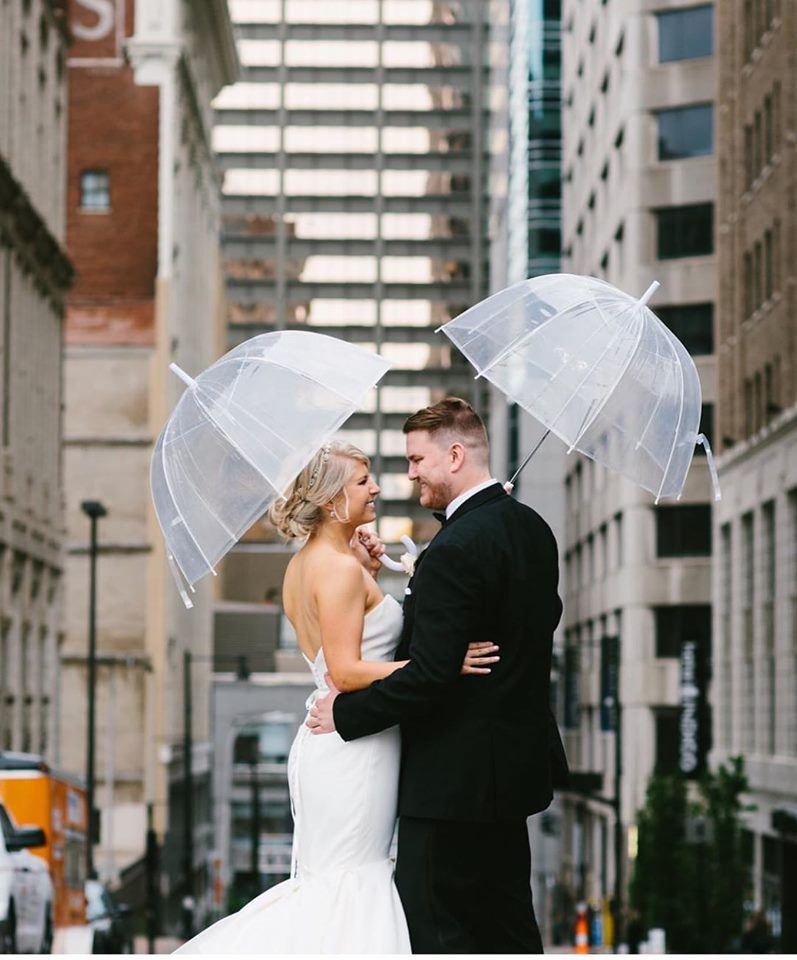 Bride And Groom Using Umbrellas In City Center