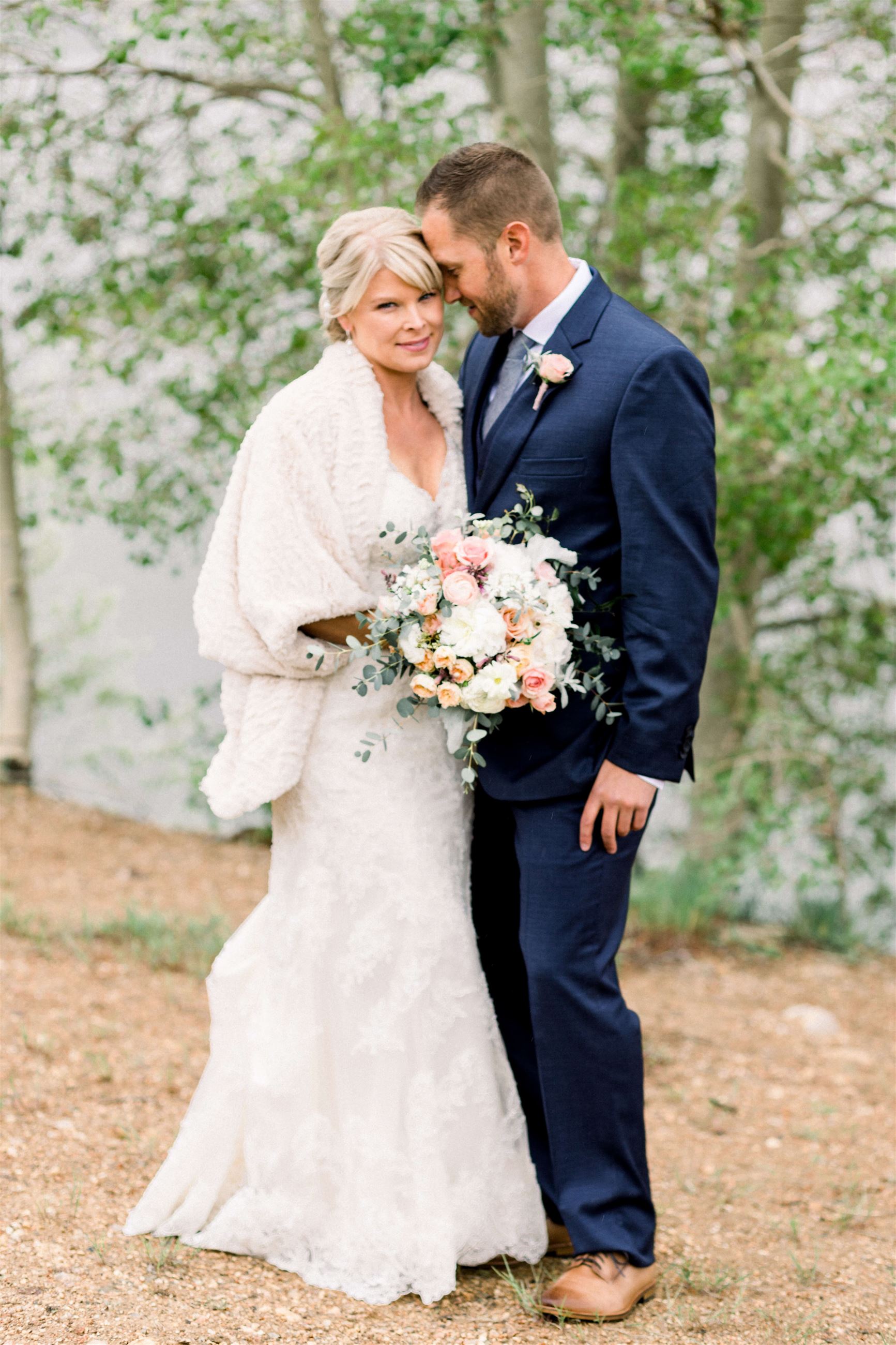 groom looking at bride wearing white dress and white coat