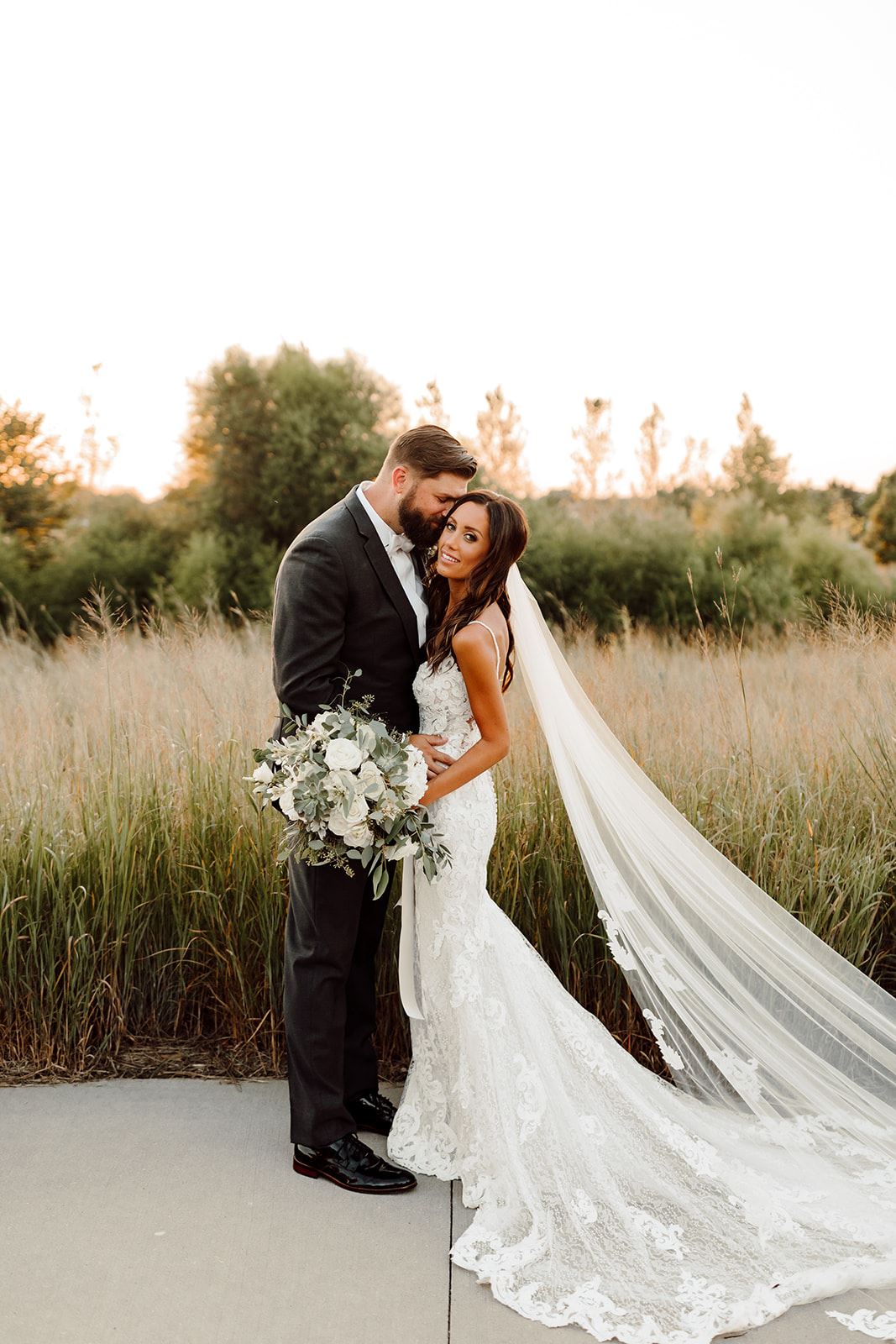 Bride and groom in front of field.