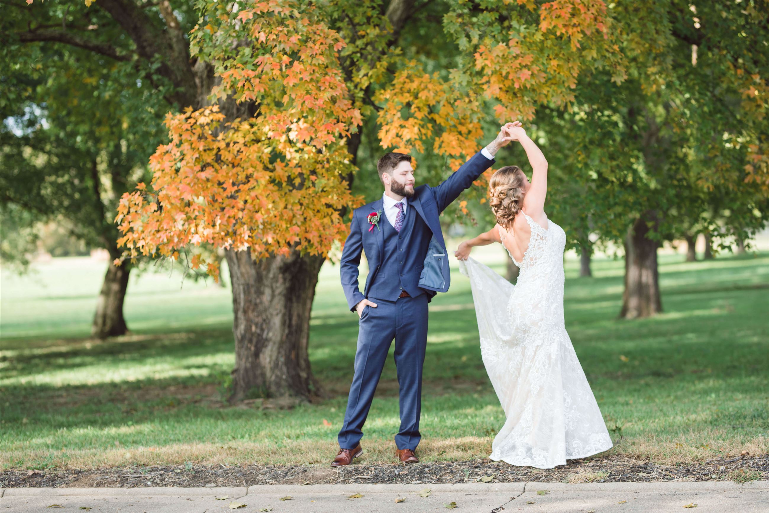 bride and groom dancing in a park